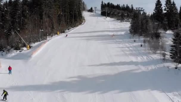 Utsikt over skiløpere går ned skråninger nær skiheiser på Ski Resort. Bukovel – stockvideo