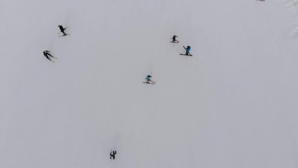 Vista aérea de los esquiadores bajan por la pista de esquí en la estación de esquí de las montañas — Vídeos de Stock