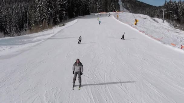 Vue aérienne Beaucoup de skieurs descendent les pistes de ski. Un drone vole bas à côté des skieurs — Video