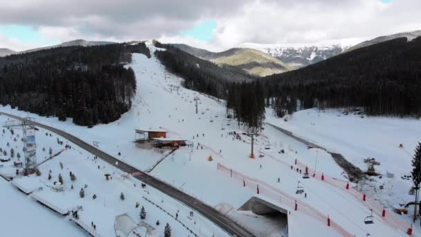 Vista aérea sobre pistas de esqui com esquiadores e elevadores de esqui no resort de esqui no inverno — Vídeo de Stock