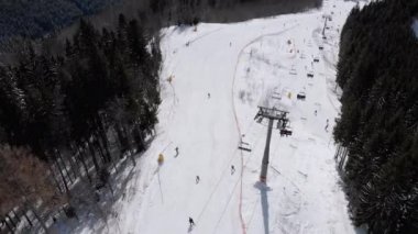 Aerial view of Ski Slopes with Skiers go Down under Ski Lifts on Ski Resort