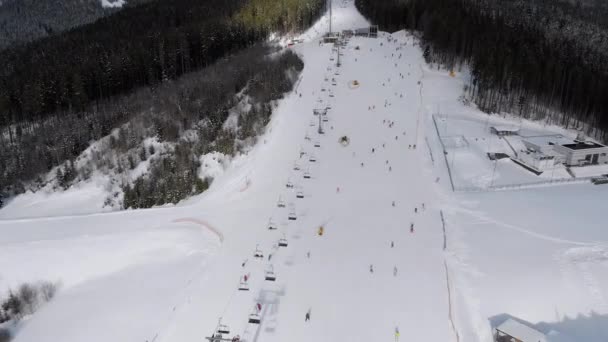 Pistas aéreas de esquí con esquiadores en estación de esquí. Bosque de abeto de montaña nevado. Bukovel. — Vídeos de Stock