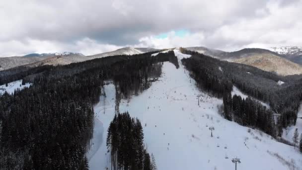 Вид с воздуха на горнолыжные склоны с лыжниками и подъемники на горнолыжном курорте в зимний период — стоковое видео