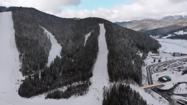 Inclinações aéreas de esqui com esquiadores no Ski Resort. Floresta de abeto de montanha nevada. Bukovel. — Vídeo de Stock