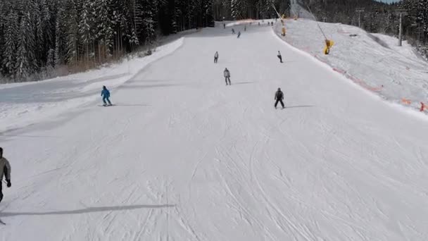 Vue aérienne Beaucoup de skieurs descendent les pistes de ski. Un drone vole bas à côté des skieurs — Video