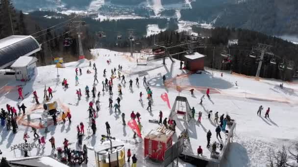 Вид с воздуха Толпа лыжников, катающихся на лыжном склоне у подъемников. Горнолыжный курорт — стоковое видео