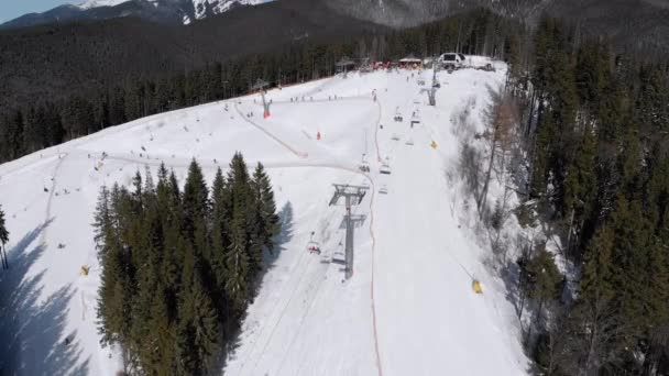 Inclinações aéreas de esqui com esquiadores e elevadores de esqui no Ski Resort. Floresta de montanha nevada — Vídeo de Stock