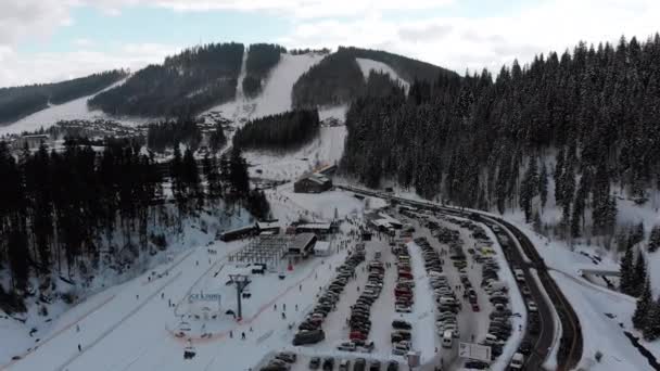 Luftaufnahme eines Skigebietes mit Parkplatz für Autos. Skipisten und Skilifte im Winter — Stockvideo