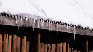 Icicles Melt and Dripping on the Sun Hanging from the Roof of Wooden House. Slow Motion