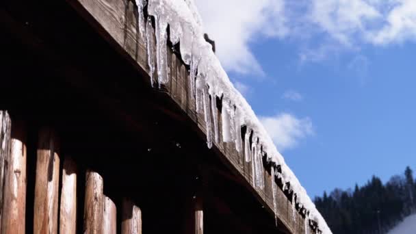 Icicles Melt and Dripping on the Sun Hanging from the Roof of Wooden House. Slow Motion — ストック動画