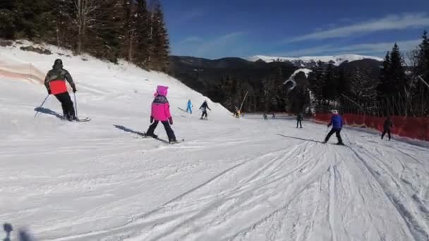 Förstapersonsvy på skidåkare och snowboardåkare glider ner på skidbacken på skidorten — Stockvideo