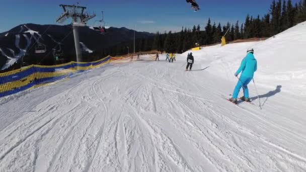 Vista en primera persona Esquiadores y snowboarders se deslizan por la pista de esquí en la estación de esquí — Vídeo de stock