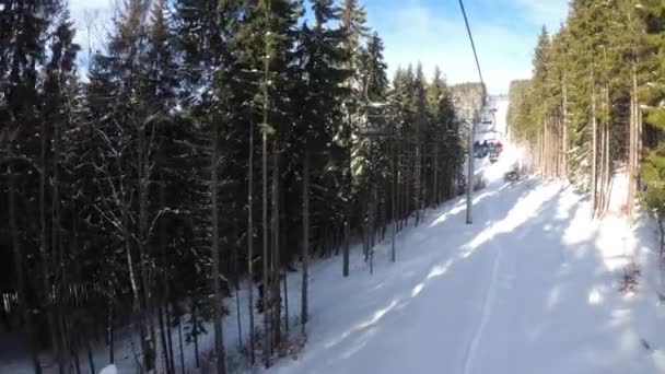 POV desde telesilla elevadora entre bosque de pino y esquiadores se levanta en teleférico — Vídeos de Stock