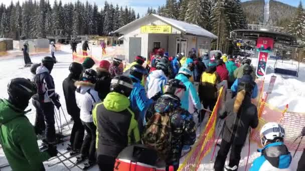 POV en multitud de esquiadores y snowboarders se aglomeran cerca del paso al telesilla — Vídeos de Stock