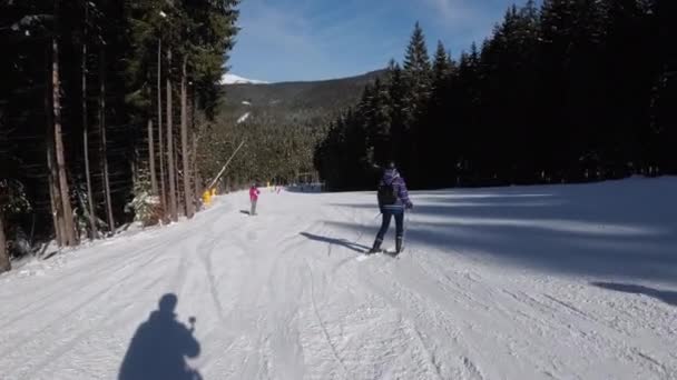 POV Principiante ragazza sugli sci e sciatori dilettanti scivolare giù sulla pista da sci presso la stazione sciistica — Video Stock