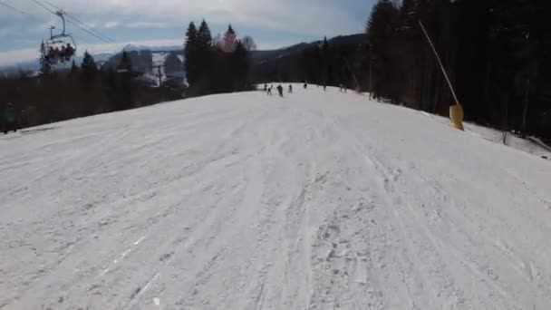 Pohled první osoby na lyžaře a snowboardisty sklouzává dolů na sjezdovce v lyžařském středisku — Stock video