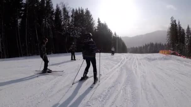 Vista en primera persona de los esquiadores aficionados y snowboarders que se deslizan por la pista de esquí en la estación de esquí — Vídeos de Stock