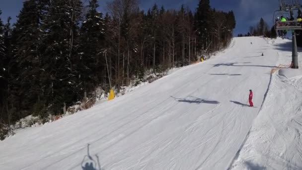 Punto de vista desde el telesilla hasta la pista de esquí nevada, los esquiadores se deslizan en la pista de esquí. — Vídeo de stock