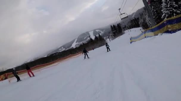 Widok pierwszej osoby na narciarzy i snowboardzistów zjeżdżalnia na stoku narciarskim w ośrodku narciarskim — Wideo stockowe