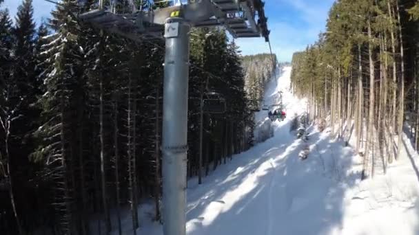 POV desde telesilla elevadora entre bosque de pino y esquiadores se levanta en teleférico — Vídeos de Stock