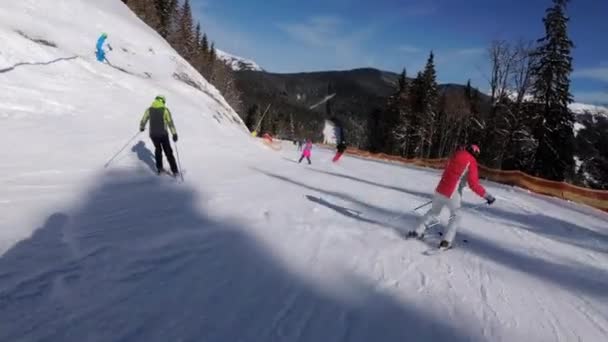 Förstapersonsvy på skidåkare och snowboardåkare glider ner på skidbacken på skidorten — Stockvideo