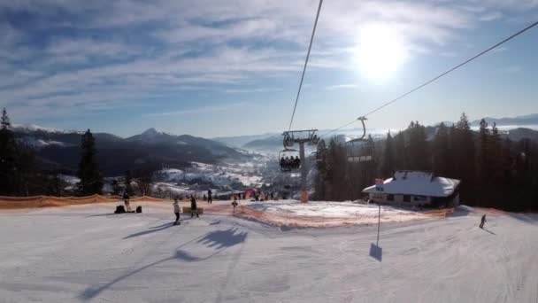 Pov vom Sessellift zur verschneiten Skipiste, Skifahrer rutschen auf der Skipiste. Skigebiet — Stockvideo