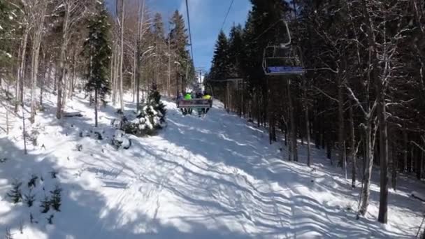POV desde telesilla elevadora entre bosque de pino y esquiadores se levanta en teleférico — Vídeo de stock
