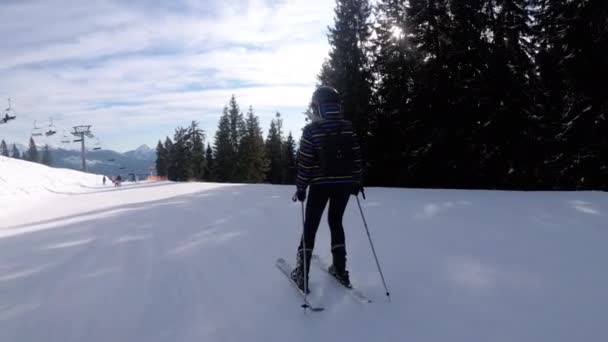 Девушка-новичок на лыжах и любительские лыжники катаются на лыжном склоне на горнолыжном курорте — стоковое видео