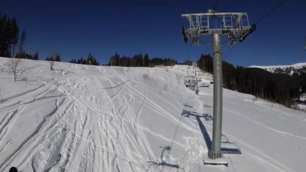 Pov från skidstolslyft till snöig skidbacke, skidåkare glider på skidbacke. — Stockvideo