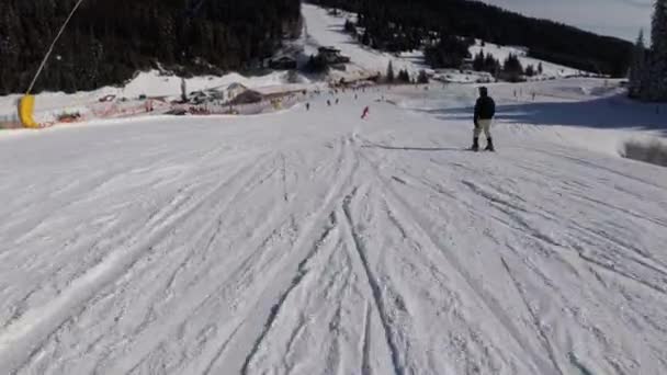 Förstapersonsvy på skidåkare och snowboardåkare glider ner på skidbacken på skidorten — Stockvideo