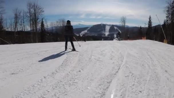 Pov Nybörjare Flicka på skidor och amatörskidåkare glider ner på skidbacken på skidorten — Stockvideo