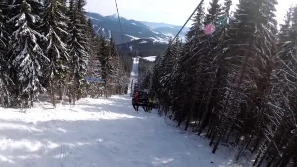 Pov från skidstolslyften mellan tallskog och skidåkare stiger upp på linbanan — Stockvideo