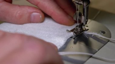 Dikiş Makinesindeki Terzi Covid-19 'u korumak için Ev Yapımı Tıbbi Yüz Maskesi Dikiyor