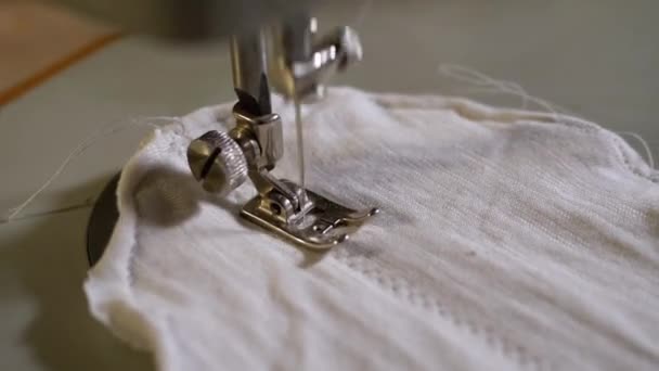Máquina de coser aguja en movimiento. Un sastre cose la máscara de la cara hecha en casa de tela — Vídeos de Stock