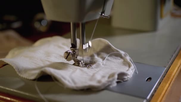Aguja de la máquina de coser en cámara lenta. Un sastre cose la máscara de la cara hecha en casa de tela — Vídeos de Stock