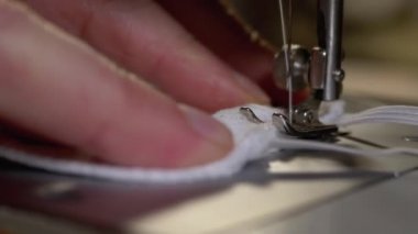 Dikiş Makinesindeki Terzi Covid-19 'u korumak için Ev Yapımı Tıbbi Yüz Maskesi Dikiyor