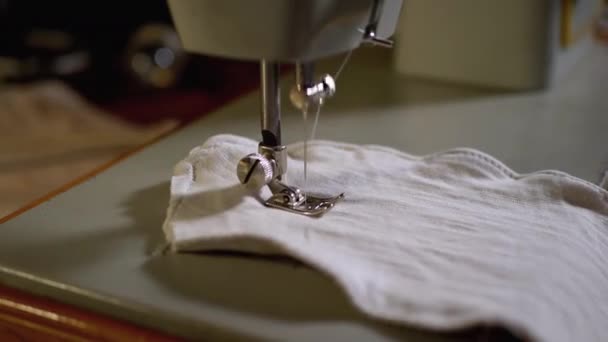Швейная машинная игла в движении. Портной шьет домашнюю маску для лица из ткани — стоковое видео