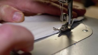 Dikiş Makinesindeki Terzi Covid-19 'u korumak için Ev Yapımı Tıbbi Yüz Maskesi Dikiyor