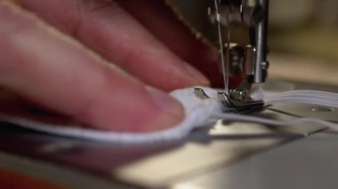 Dikiş Makinesindeki Terzi Covid-19 'u korumak için Ev Yapımı Tıbbi Yüz Maskesi Dikiyor