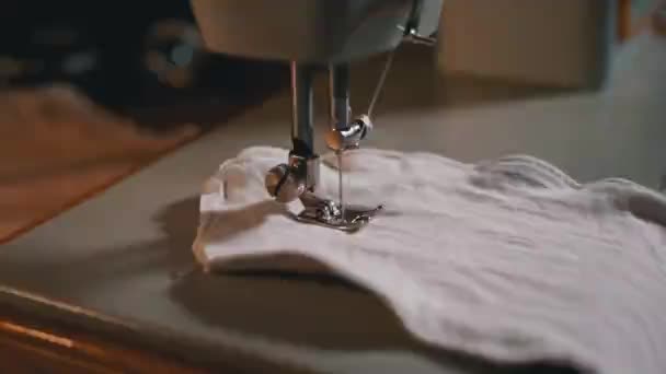 Швейная машинная игла в движении. Портной шьет домашнюю маску для лица из ткани — стоковое видео