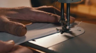 Dikiş Makinesindeki Terzi Covid-19 'u korumak için Ev Yapımı Tıbbi Yüz Maskesi Dikiyor