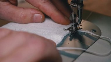 Dikiş Makinesindeki Terzi Covid-19 'u korumak için Ev Yapımı Tıbbi Yüz Maskesi Dikiyor