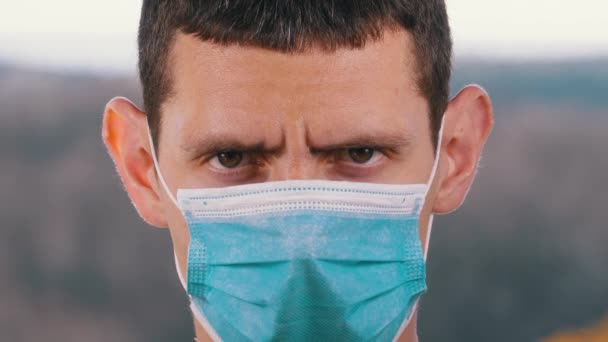Tıbbi Koruyucu Yüz Maskeli Genç Adam Sokak Arkaplanındaki Kameraya Bakıyor — Stok video