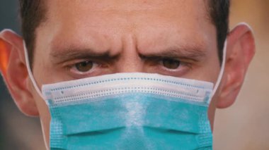 Koruyucu Yüz Maskeli Adam Akıllı Telefona bakar ve onu Sokakta Eller 'de tutar.