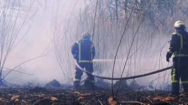 Ekipmandaki iki itfaiyeci yangın söndürme hortumuyla söndürüyorlar. Yavaş Hareket