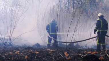 Ekipmandaki iki itfaiyeci yangın söndürme hortumuyla söndürüyorlar. Yavaş Hareket