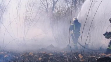 Ekipmandaki iki itfaiyeci yangın söndürme hortumuyla söndürüyorlar. Yavaş Hareket
