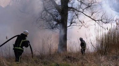 Ekipmandaki iki itfaiyeci yangın söndürme hortumuyla söndürüyorlar. Yavaş Hareket