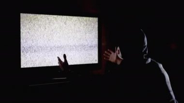 Kapüşonlu ve Tıbbi Maskeli Siluet Adam TV 'de Eller Yukarı Parazit İzliyor