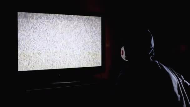 Silhouette de l'homme dans le capot et masque médical Regarder la télévision avec interférence statique — Video